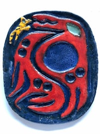 a ceramic plate with a red and blue bird on it